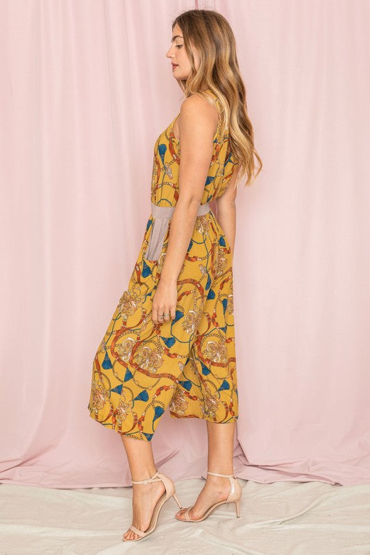 A person wearing a Blouson Chain Tassel Print Cropped Jumpsuit stands against a plain white background, accentuating the outfit with a chic chain tassel.