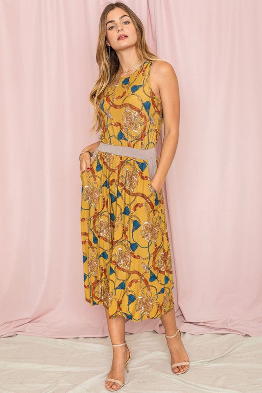 A person wearing a Blouson Chain Tassel Print Cropped Jumpsuit stands against a plain white background, accentuating the outfit with a chic chain tassel.