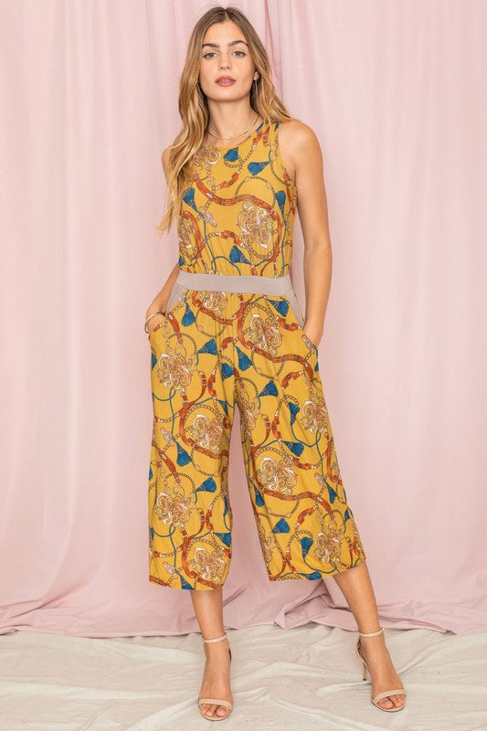 A person wearing a Blouson Chain Tassel Print Cropped Jumpsuit stands against a plain white background, accentuating the outfit with a chic chain tassel.