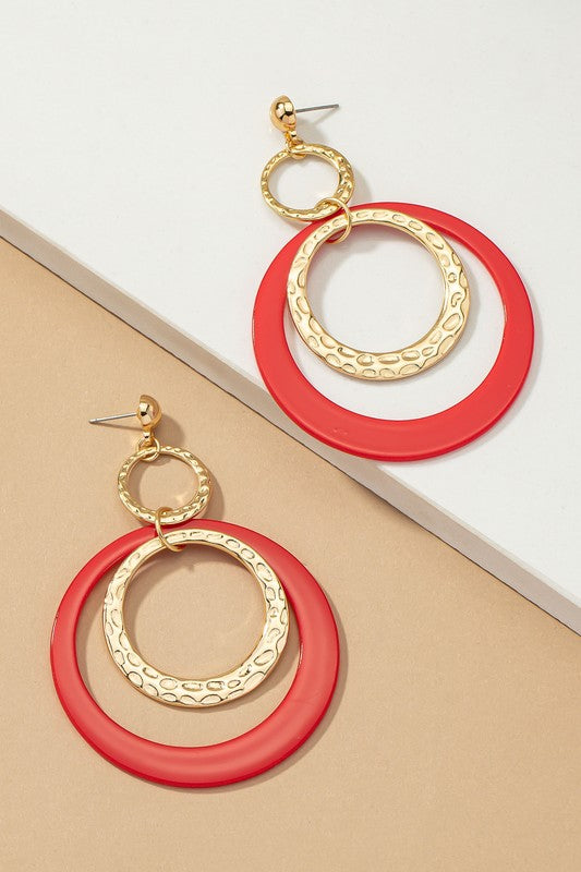 Five pairs of hoop drop earrings featuring hammered metal and vibrant acrylic accents are displayed against a beige and white backdrop, highlighting their shiny gold plating.