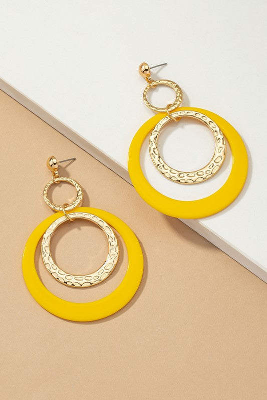 Five pairs of hoop drop earrings featuring hammered metal and vibrant acrylic accents are displayed against a beige and white backdrop, highlighting their shiny gold plating.