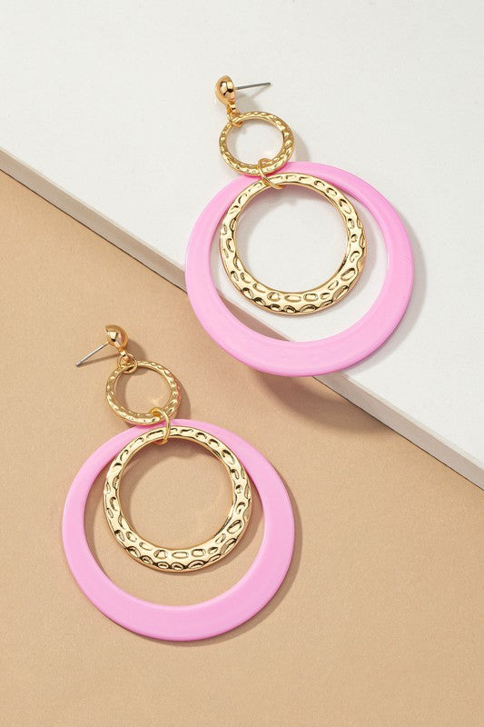Five pairs of hoop drop earrings featuring hammered metal and vibrant acrylic accents are displayed against a beige and white backdrop, highlighting their shiny gold plating.