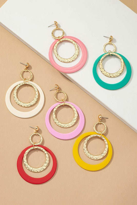 Five pairs of hoop drop earrings featuring hammered metal and vibrant acrylic accents are displayed against a beige and white backdrop, highlighting their shiny gold plating.