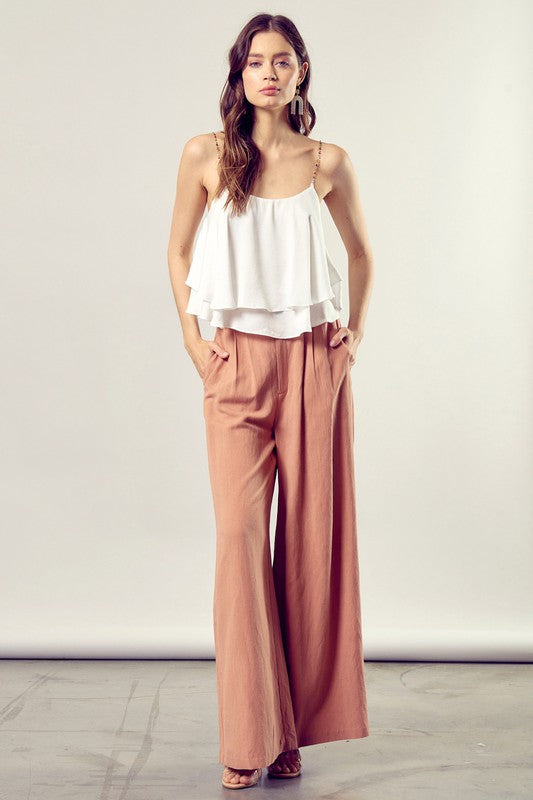 A woman wearing the Beaded Shoulder Strap Cami Top paired with peach pants.