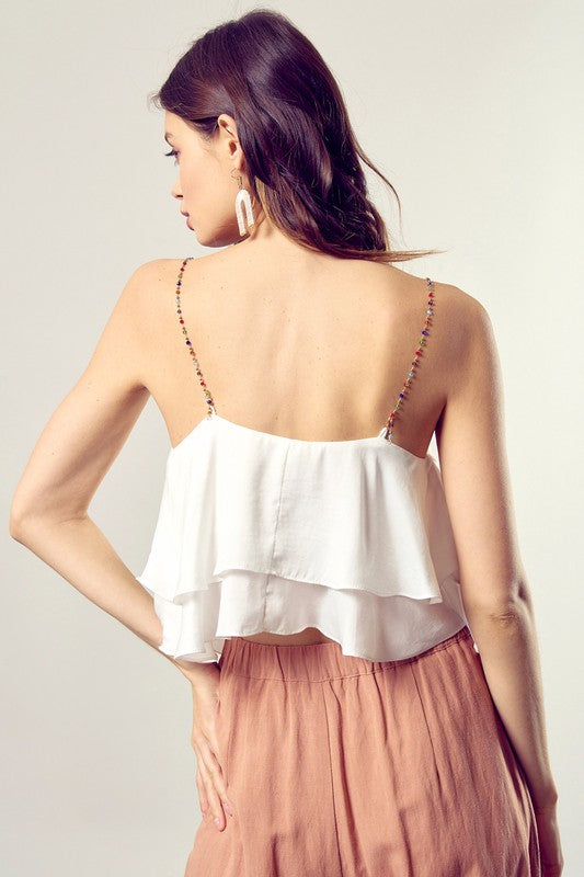 A woman wearing the Beaded Shoulder Strap Cami Top paired with peach pants.