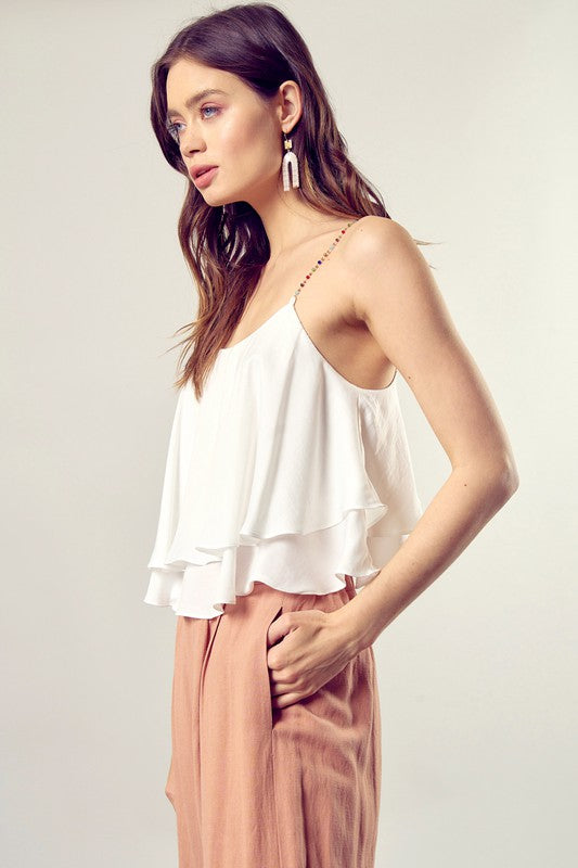 A woman wearing the Beaded Shoulder Strap Cami Top paired with peach pants.