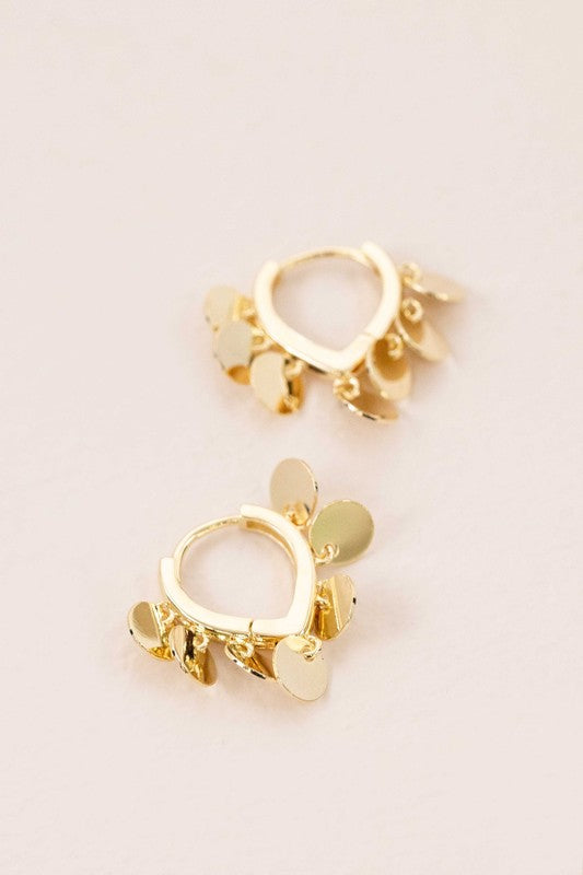 The Agra Huggie Hoop Earrings are an elegant pair of 10k gold-plated hoops adorned with delicate gold circle charms.