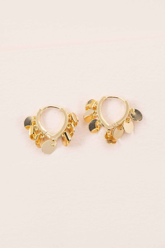 The Agra Huggie Hoop Earrings are an elegant pair of 10k gold-plated hoops adorned with delicate gold circle charms.