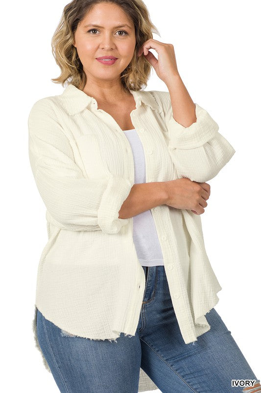 A person wearing the Plus Oversized Raw Edge Shirt in dusty blush over a white top and jeans, posing with one hand near their chin, capturing the essence of a casual wardrobe look.