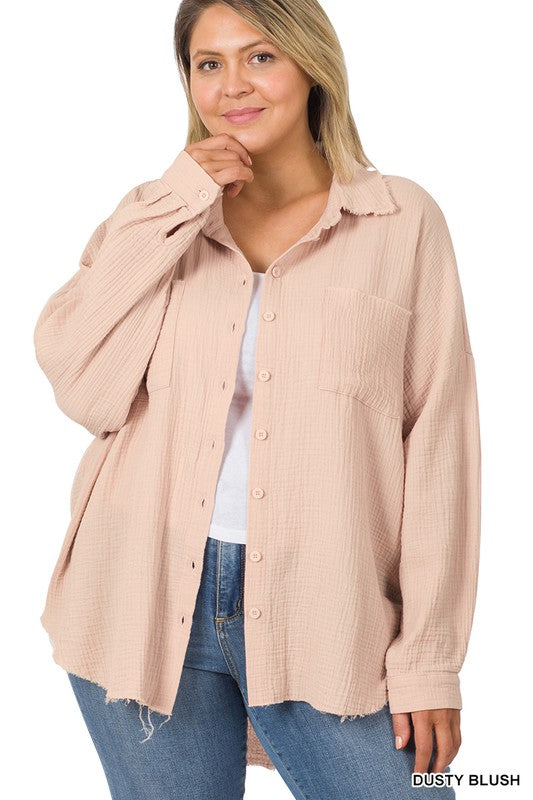 A person wearing the Plus Oversized Raw Edge Shirt in dusty blush over a white top and jeans, posing with one hand near their chin, capturing the essence of a casual wardrobe look.