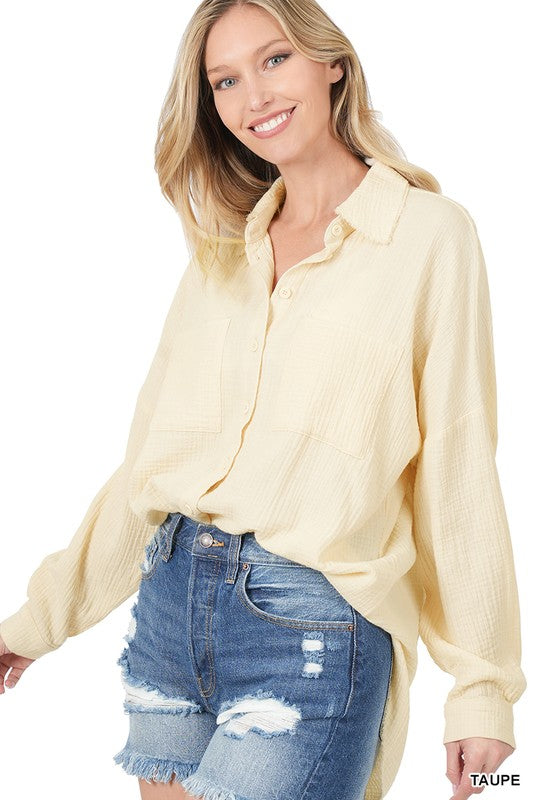 A woman wearing an Oversized Raw Edge Shirt poses gracefully, showcasing a black hat, a white lace top, denim shorts, and effortlessly resting her hand on the hat.