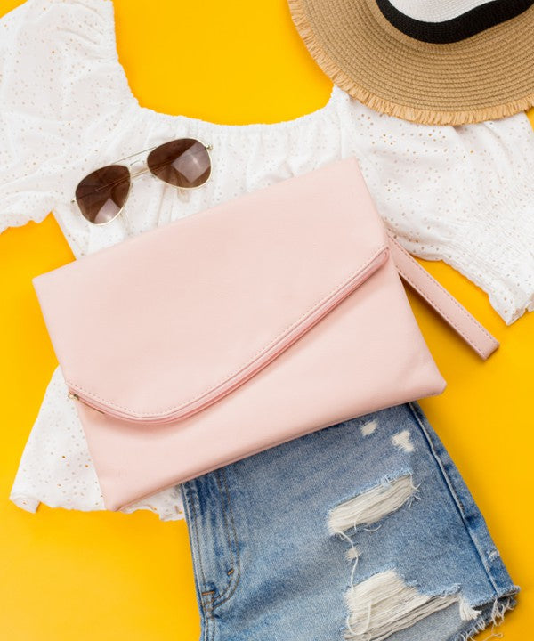 A woman in a white top holds the Foldover Envelope Clutch in black while sitting.