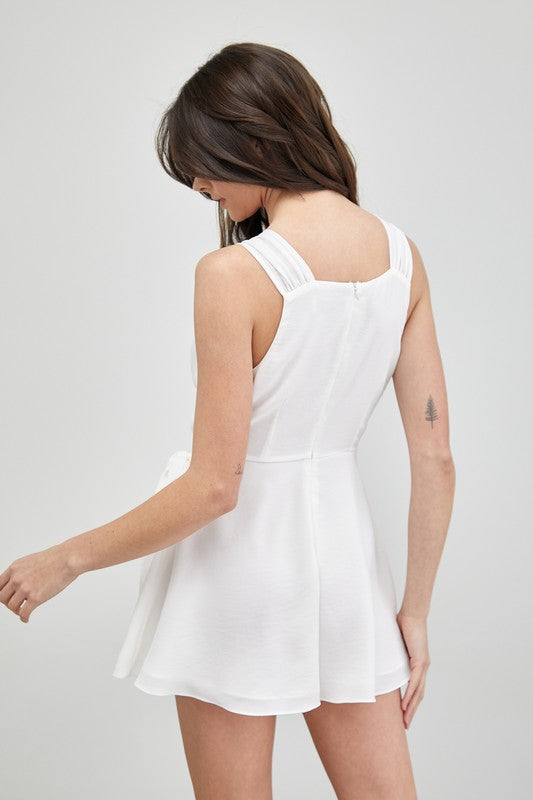 A woman in a sleeveless Trim Detail Side Tie Romper gazes to the side, showcasing a versatile wardrobe addition.