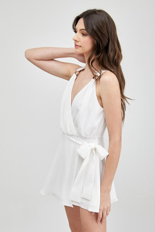 A woman in a sleeveless Trim Detail Side Tie Romper gazes to the side, showcasing a versatile wardrobe addition.