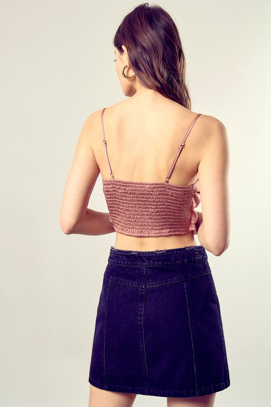 A person wearing a Front Tie-Up Cami Crop Top in light blue, featuring a V-neckline, paired with brown pants stands against a plain background, perfectly capturing the essence of a summer wardrobe.