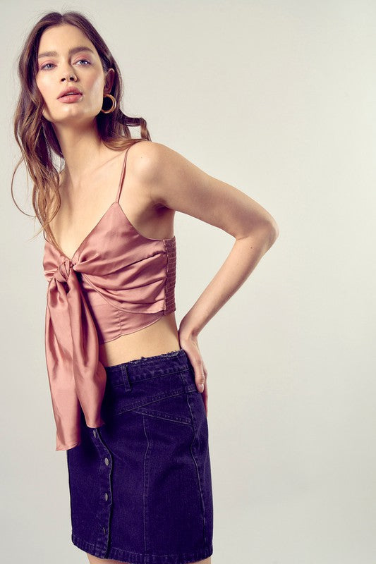 A person wearing a Front Tie-Up Cami Crop Top in light blue, featuring a V-neckline, paired with brown pants stands against a plain background, perfectly capturing the essence of a summer wardrobe.