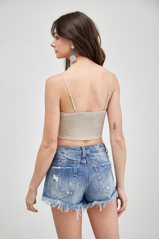 A person wearing a Front Tie-Up Cami Crop Top in light blue, featuring a V-neckline, paired with brown pants stands against a plain background, perfectly capturing the essence of a summer wardrobe.