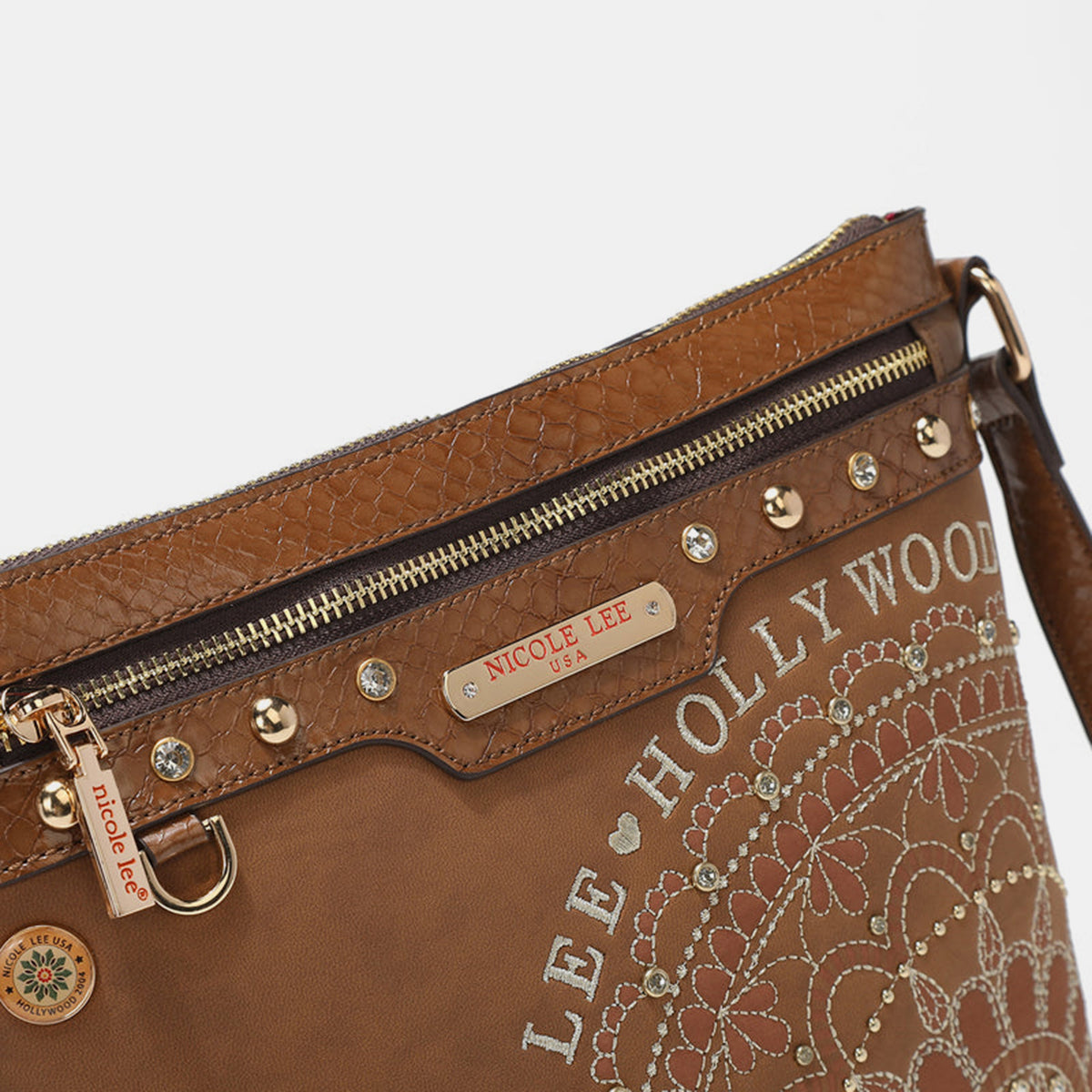 The Nicole Lee USA Metallic Stitching Embroidery Inlaid Rhinestone Crossbody Bag is a brown vegan leather accessory adorned with intricate white designs and text reading "Nicole Lee Hollywood USA" on the front. It features diamond rhinestones, multiple zippered compartments, and an adjustable strap.