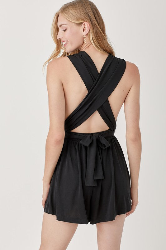 Person wearing a black halter neck knit romper with waist-banded detail, standing against a plain background.