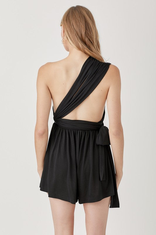 Person wearing a black halter neck knit romper with waist-banded detail, standing against a plain background.