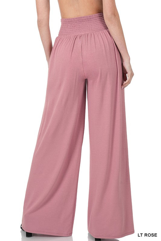 A person dons Smocked Waist Wide Leg Pants in coral pink with a pleated design and a relaxed fit, paired effortlessly with sandals.