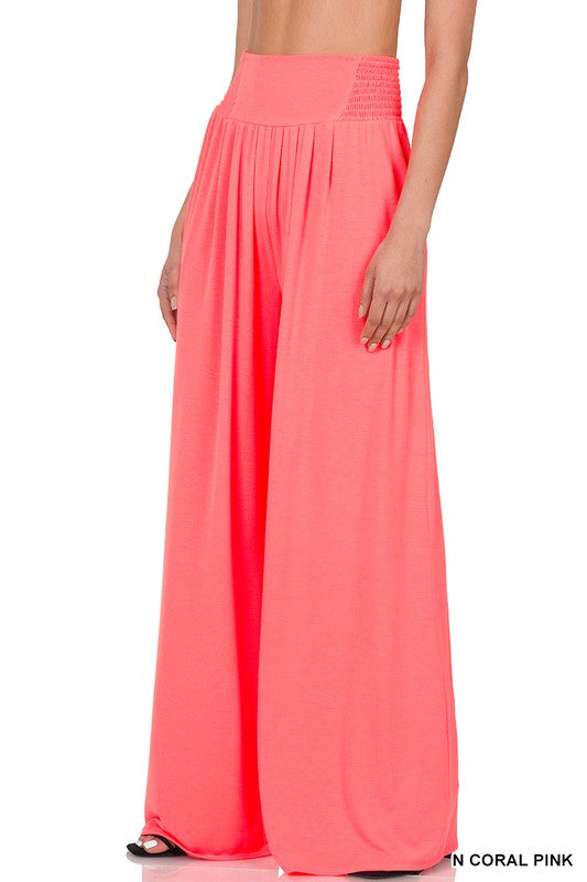 A person dons Smocked Waist Wide Leg Pants in coral pink with a pleated design and a relaxed fit, paired effortlessly with sandals.