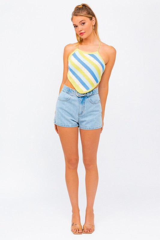 A person wearing the "Sleeveless Knit Cropped Top" and denim shorts stands against a plain background, with one hand on their head.