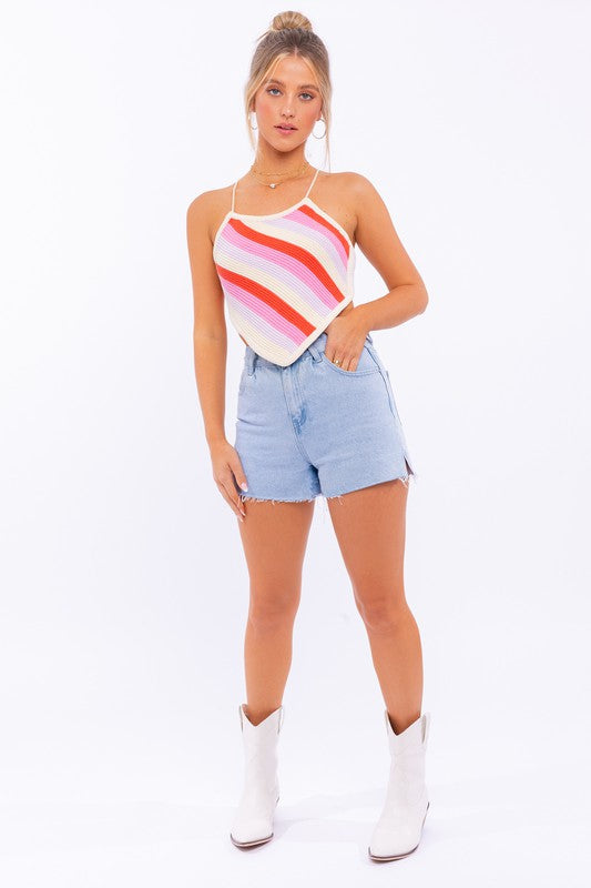 A person wearing the "Sleeveless Knit Cropped Top" and denim shorts stands against a plain background, with one hand on their head.