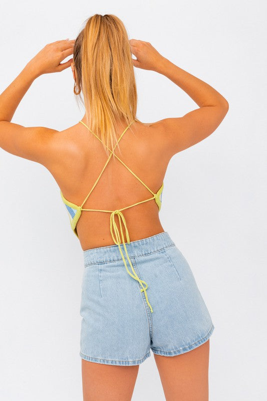 A person wearing the "Sleeveless Knit Cropped Top" and denim shorts stands against a plain background, with one hand on their head.