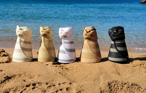 Woman in a white bikini holding her Marled Stripe Roll up Bow Visor while facing the sea.
