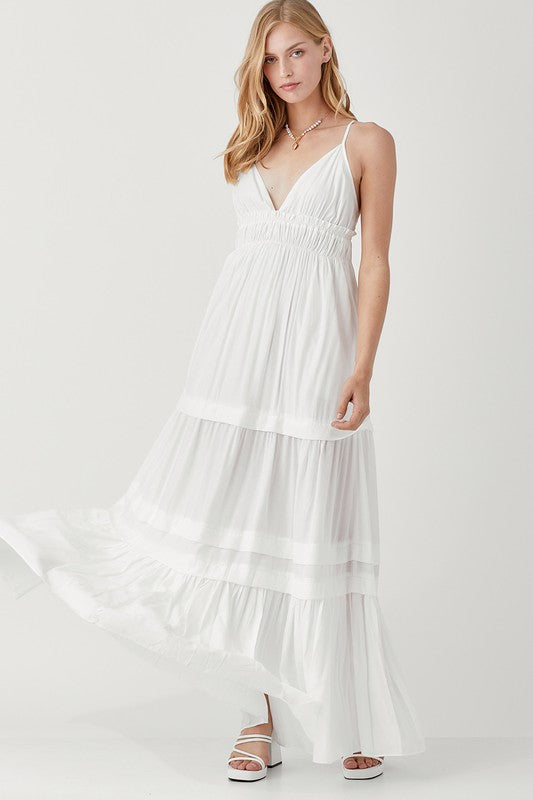 Dressed in a Shirred Ruffle Folded Detail Maxi Dress, featuring a striking blue color, plunging neckline, and stylish ruffle accents, the individual stands against a plain background exuding an effortless boho style.