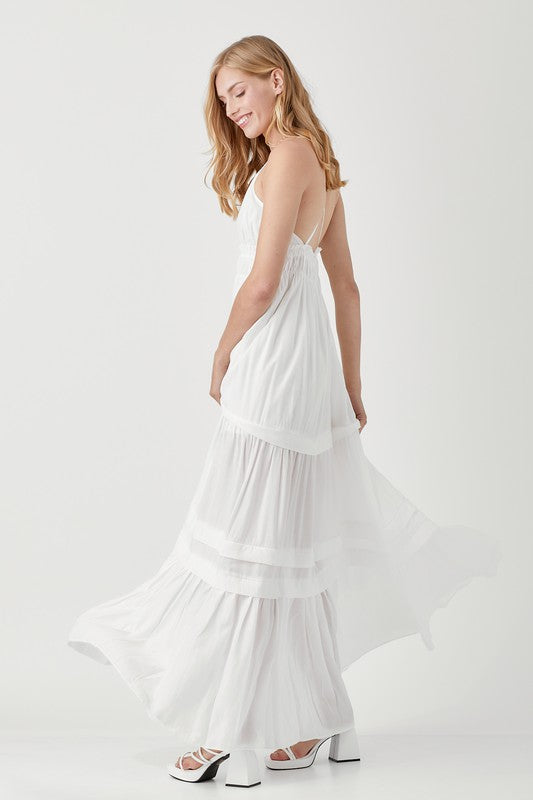 Dressed in a Shirred Ruffle Folded Detail Maxi Dress, featuring a striking blue color, plunging neckline, and stylish ruffle accents, the individual stands against a plain background exuding an effortless boho style.