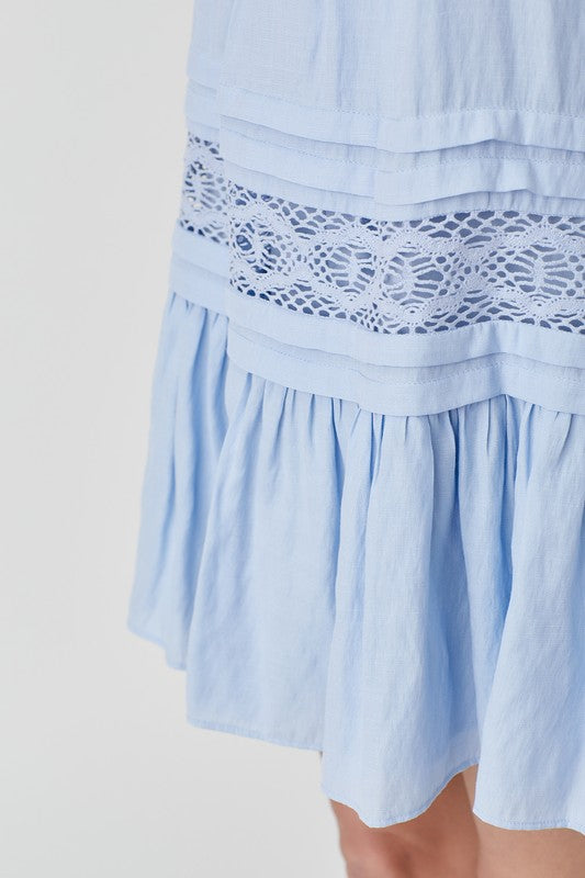 A woman wearing the Halter Neck Trim Lace with Folded Detail Dress in light blue, stands against a plain background.