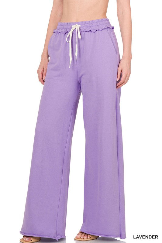 Against a plain white backdrop, someone models the French Terry Drawstring Waist Raw Edge Hem Pants in light blue. The wide-leg design and soft fabric provide a relaxed style, while the drawstring waist enhances comfort for any casual gathering.