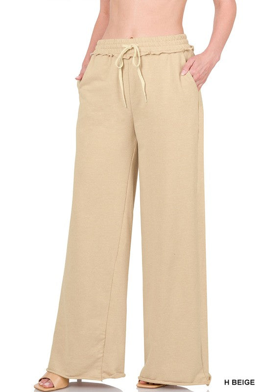 Against a plain white backdrop, someone models the French Terry Drawstring Waist Raw Edge Hem Pants in light blue. The wide-leg design and soft fabric provide a relaxed style, while the drawstring waist enhances comfort for any casual gathering.