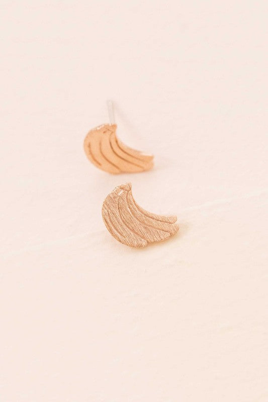 Six pairs of Banana Earrings, crafted in a blend of sterling silver with gold and rose gold accents, are arranged in a neat line on a light background. This collection adds a touch of quirky jewelry charm to any ensemble.