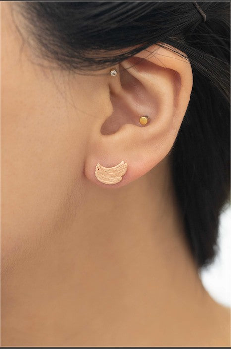 Six pairs of Banana Earrings, crafted in a blend of sterling silver with gold and rose gold accents, are arranged in a neat line on a light background. This collection adds a touch of quirky jewelry charm to any ensemble.