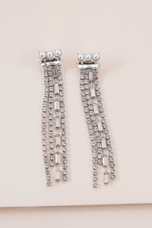 Close-up of a person wearing Gatsby Dangle Earrings, featuring long sterling silver strands adorned with small gems, set against a neutral background.