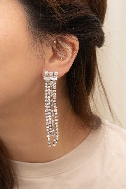 Close-up of a person wearing Gatsby Dangle Earrings, featuring long sterling silver strands adorned with small gems, set against a neutral background.