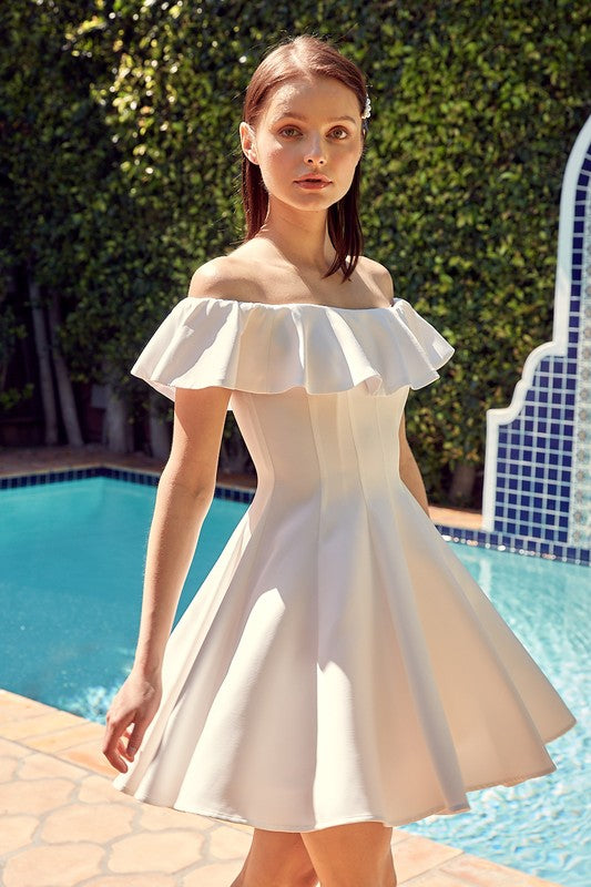 A woman in the quintessential A Line Ruffle Dress poses by a pool, the dress's flattering fit accentuated by the vibrant greenery in the background.