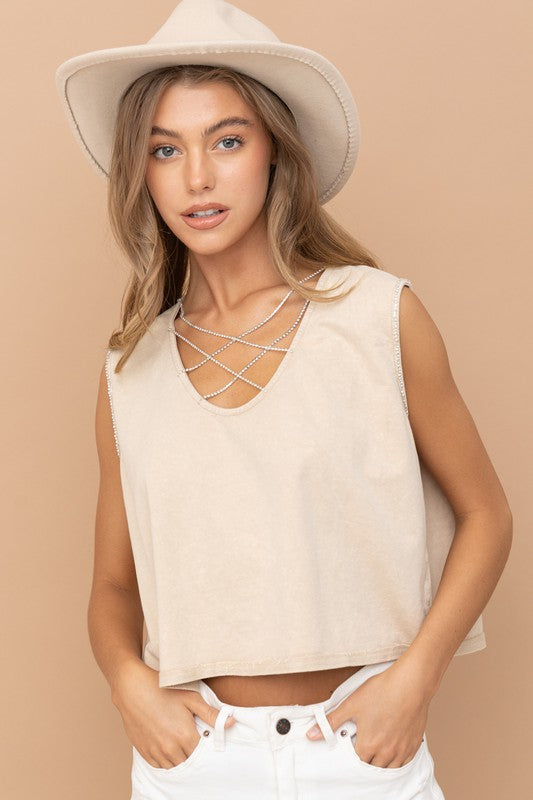 Wearing a Mineral Washed Rhinestone Tank with decorative pearl chains and light blue jeans, a person smiles while looking to the side against a beige background.