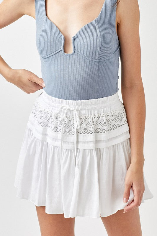 A person wearing a Trim Lace with Folded Detail Skirt paired with a white top.