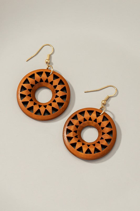 The NEW COLORS Cutout wood circle drop earrings, showcasing exquisite geometric patterns in black, brown, yellow, and orange, are elegantly arranged on a white surface.