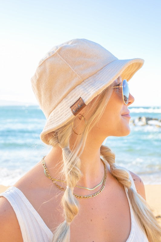 Woman wearing a CC Terry Cloth Bucket Hat and sunglasses at the beach.