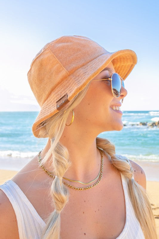 Woman wearing a CC Terry Cloth Bucket Hat and sunglasses at the beach.