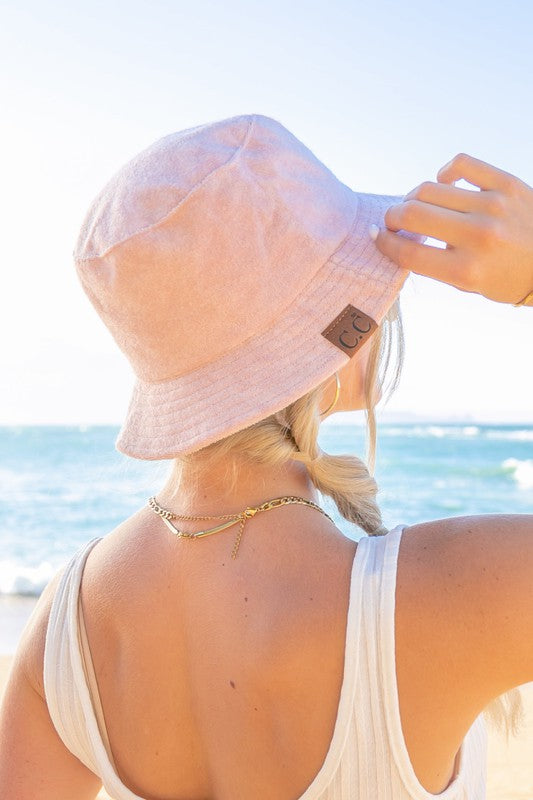 Woman wearing a CC Terry Cloth Bucket Hat and sunglasses at the beach.