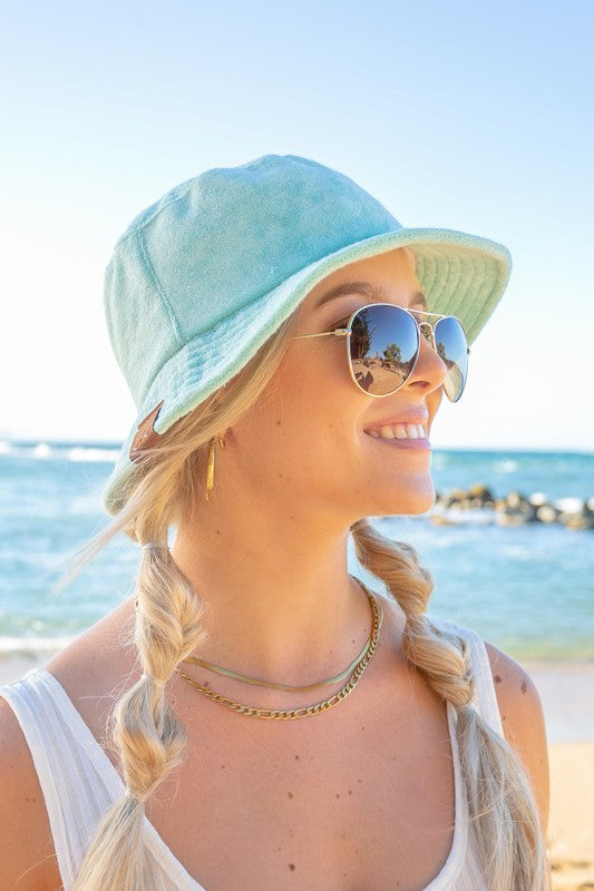 Woman wearing a CC Terry Cloth Bucket Hat and sunglasses at the beach.