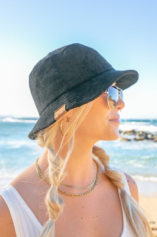 Woman wearing a CC Terry Cloth Bucket Hat and sunglasses at the beach.