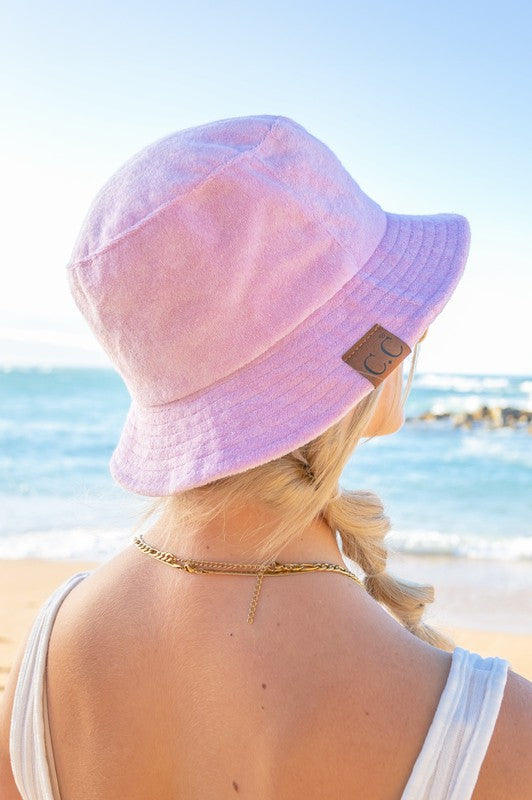 Woman wearing a CC Terry Cloth Bucket Hat and sunglasses at the beach.