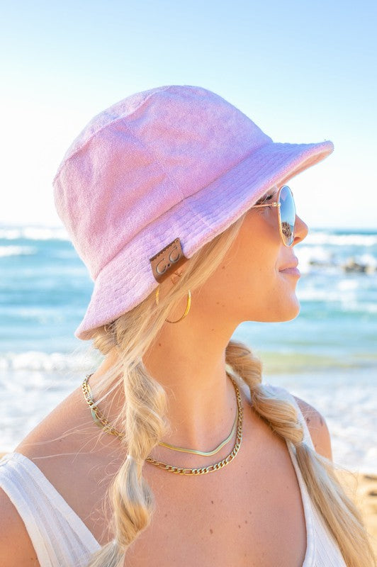 Woman wearing a CC Terry Cloth Bucket Hat and sunglasses at the beach.